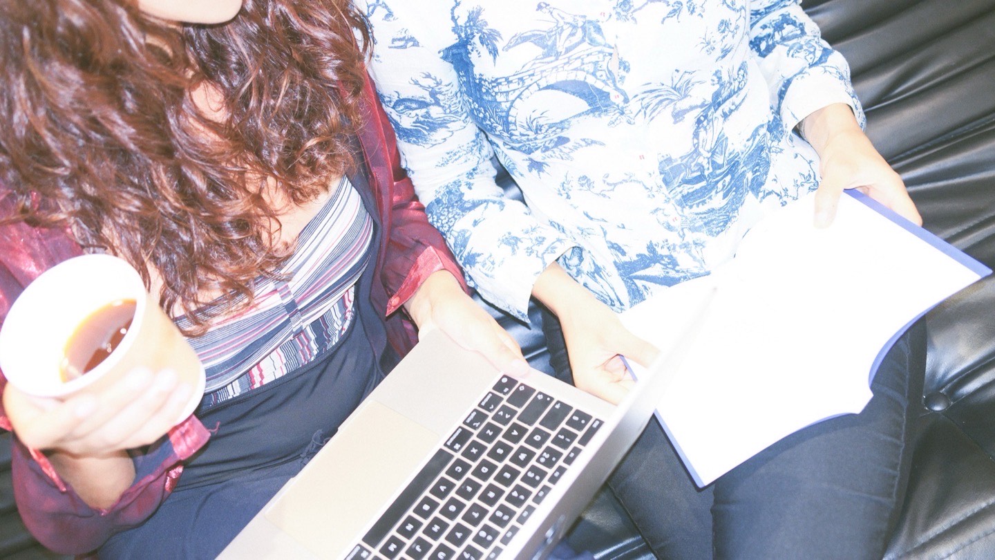 The two of us side by side on the studio sofa, a laptop open on one lap, a coffee in one hand and a notebook in the other.